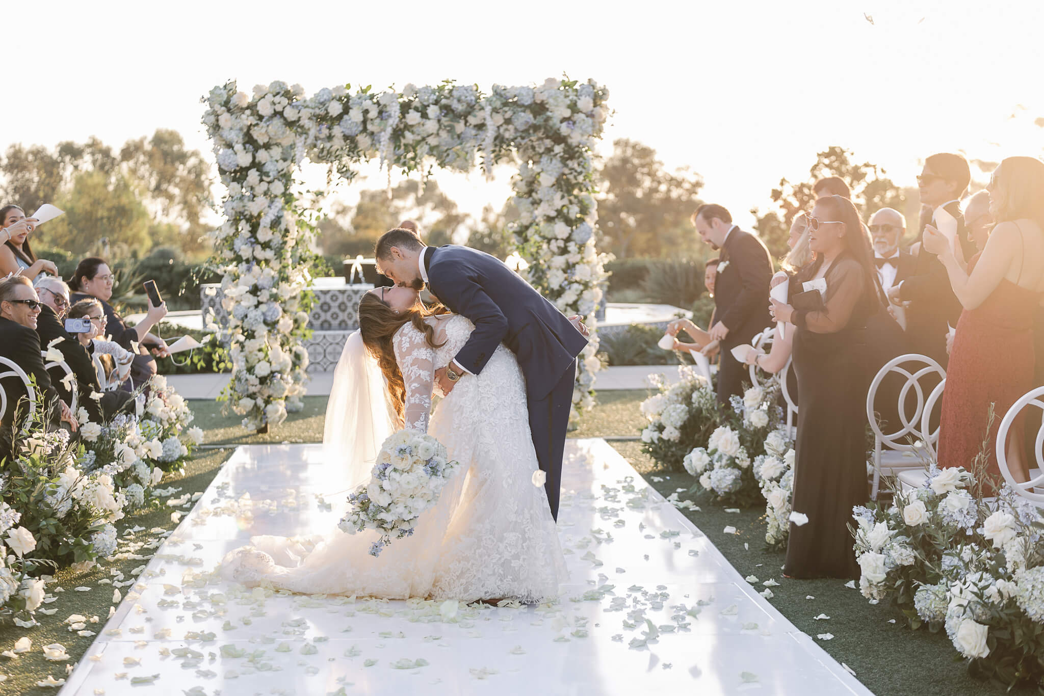 bride and groom kissing in front of flower arch at park hyatt aviara in san diego